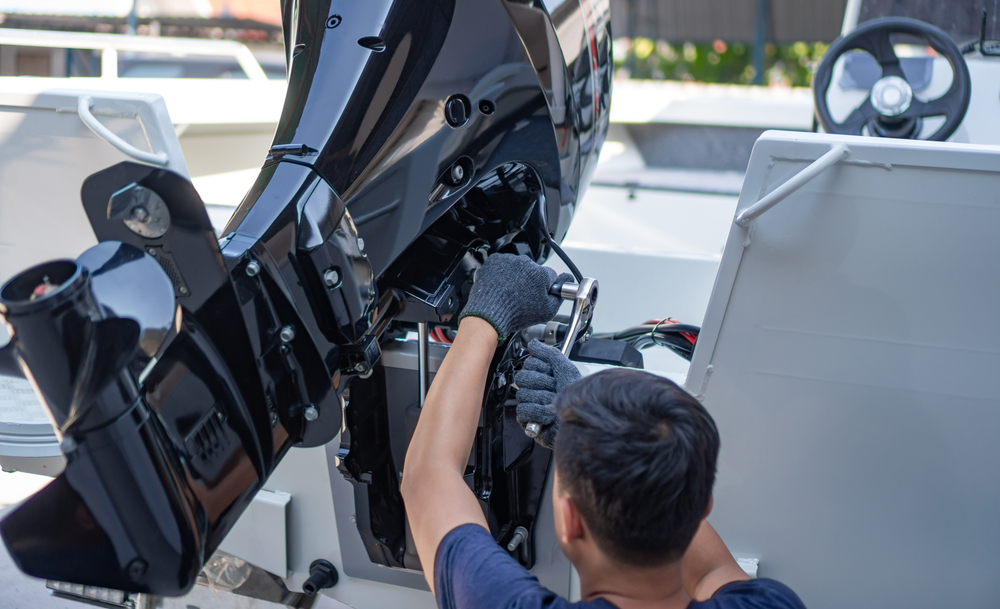 Outboard motor with powerhead lifted during servicing at the Outlaw Marine workshop